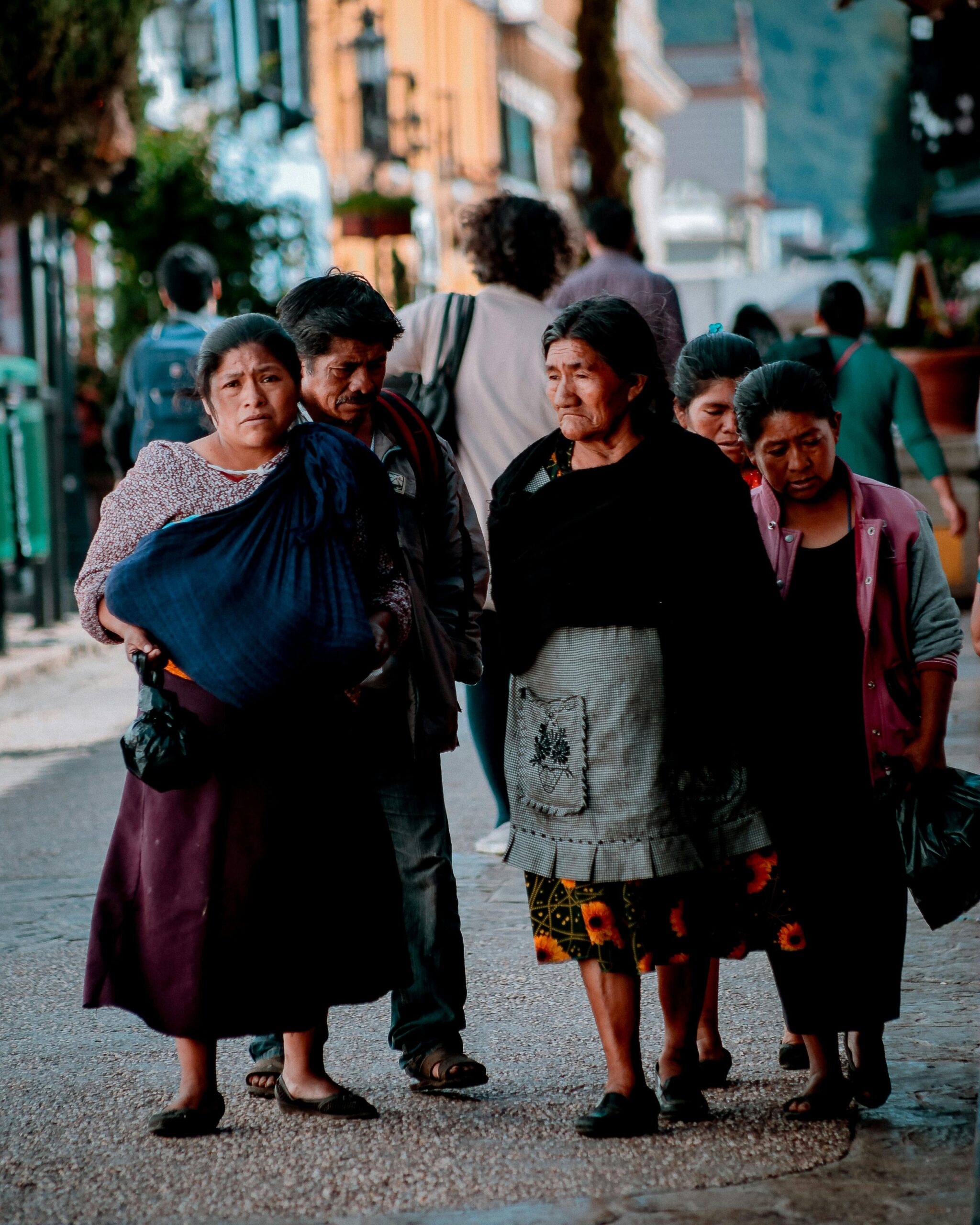 A group of people walking down a vibrant street in San Cristobal de las Casas, Mexico.